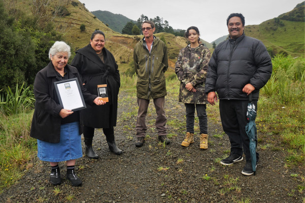 5 people stand in farmland holding a trophy and certificate