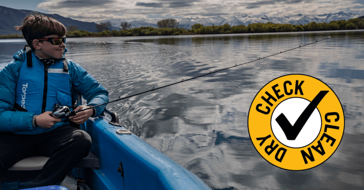 A boy fishing from a kayak with a yellow 'Check Clean Dry' logo to the right of him